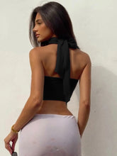 Woman wearing a black halter top and white pants- back view